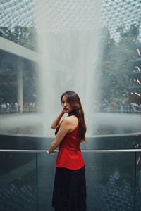 Portrait of woman standing by fountain outdoors