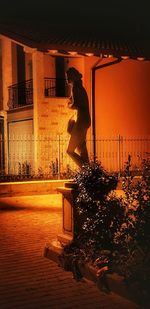 Woman standing by illuminated building at night