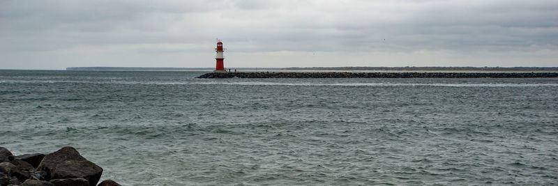 Lighthouse by sea against sky