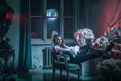 Portrait of woman in costume sitting on chair at home during night