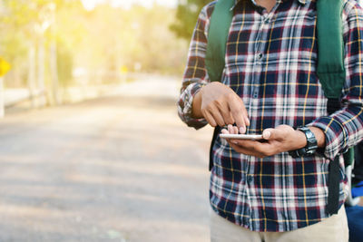 Man holding phone while standing on street