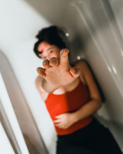 Young woman showing stop gesture against tiled wall in bathroom