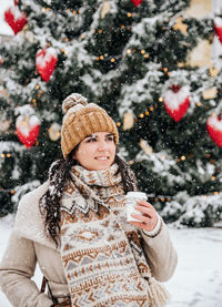 Portrait of a young woman drinking coffee from a paper coffee to go cup. winter, christmas, snowing.