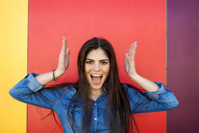 Portrait of screaming young woman in front of colourful wall