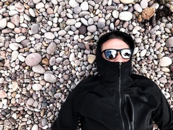 Directly above shot of man wearing sunglasses while lying on pebbles