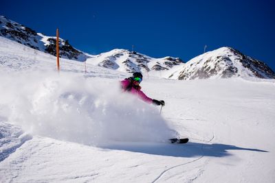 Woman skiing on snowy field against clear blue sky