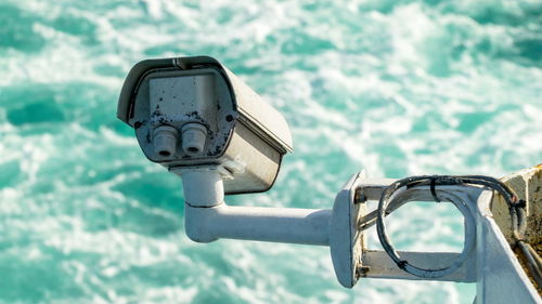 Close-up of coin-operated binoculars against lake