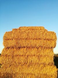 Hay bales on field against clear sky