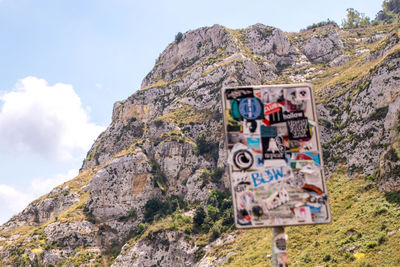 Low angle view of text on rock against sky