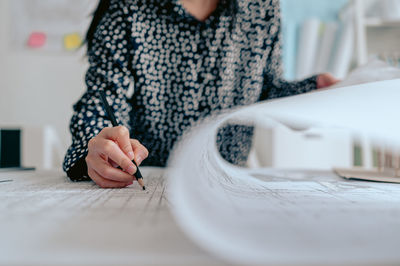 Midsection of woman sitting on table at home