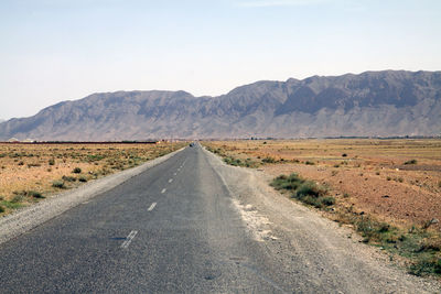 Road amidst desert against clear sky