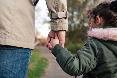 Daughter holding hands with father in park during autumn