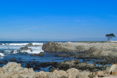 Rocks on beach against blue sky