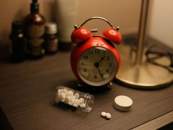 Close-up of pill bottle and alarm clock on table