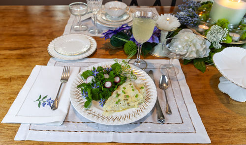 Cod fish and spring green salad on fine china with a table decorated for easter.