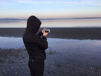Full length of woman photographing on beach