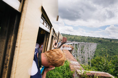 Rear view of man peeking through train window