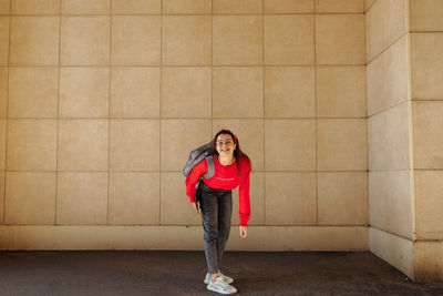 Portrait of young woman standing against wall