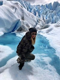 Portrait of mature woman crouching at glacier 