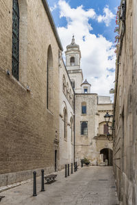 Footpath amidst buildings against sky