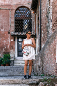 Portrait of young woman standing against wall