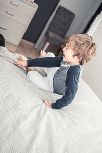 Boy sitting on bed at home