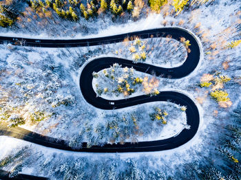 High angle view of winding road amidst snow covered trees in forest