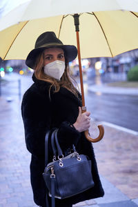 Portrait of woman wearing mask holding umbrella