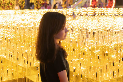 Side view of woman looking at illuminated lights