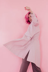 Midsection of woman standing against pink background