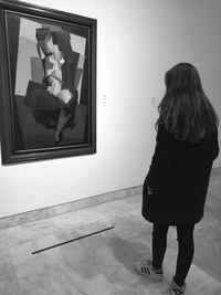 Rear view of young woman standing on window