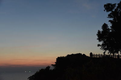 Silhouette trees by sea against sky during sunset