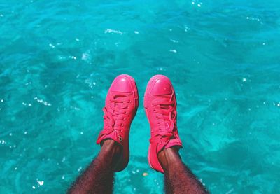 Low section of man wearing pink shoes poolside 
