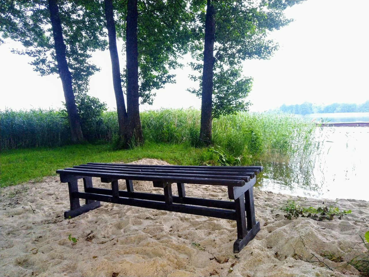 EMPTY BENCH ON TABLE BY LAKE