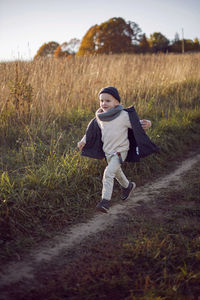 Funny fashionable boy child run on the field in autumn