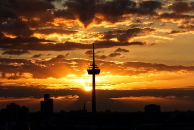 Silhouette of buildings against cloudy sky during sunset