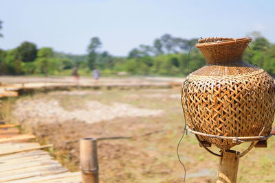 Close-up of wicker basket on field against sky