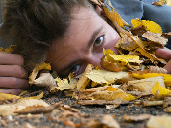 Teenager peeking from behind dry leaves