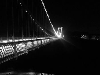 Light trails on bridge in city against sky at night