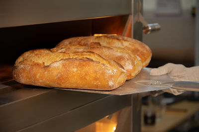 Close-up of a baker's shovel taking freshly baked artisan bread out of the oven. bread production