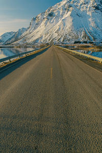 Empty road leading towards snow covered mountain