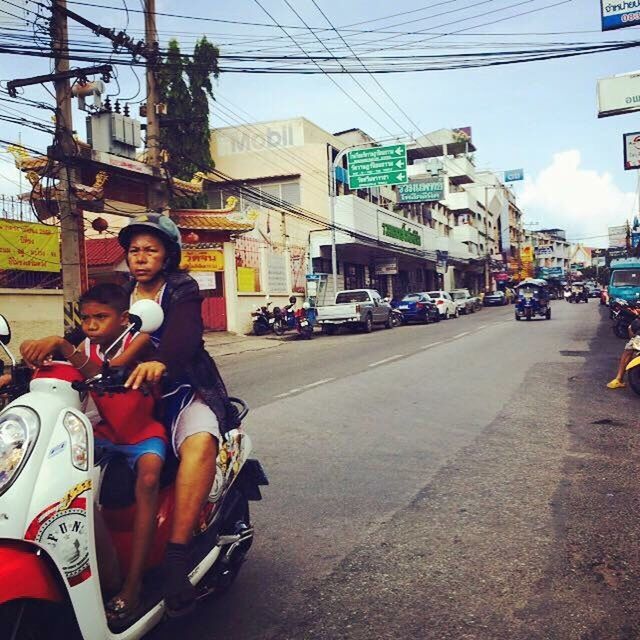 PORTRAIT OF A SMILING YOUNG WOMAN SITTING IN CITY