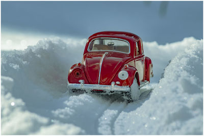 Red car in snow against sky