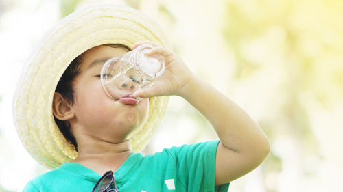 Close-up of cute boy drinking water outdoors