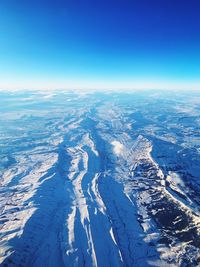 Aerial view of snowcapped mountains against blue sky