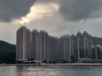 Modern buildings by river against sky in city