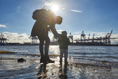 People on pier at beach against sky