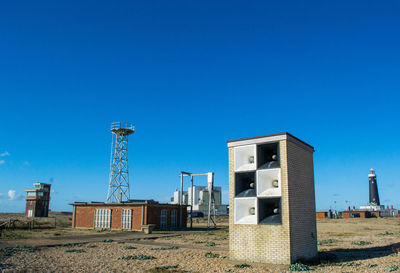 Built structures on field against clear blue sky