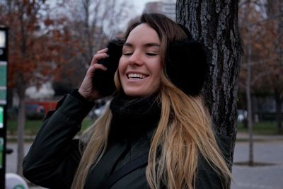 Portrait of a smiling young woman against tree during winter