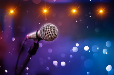Close-up of microphone in stand against illuminated lights